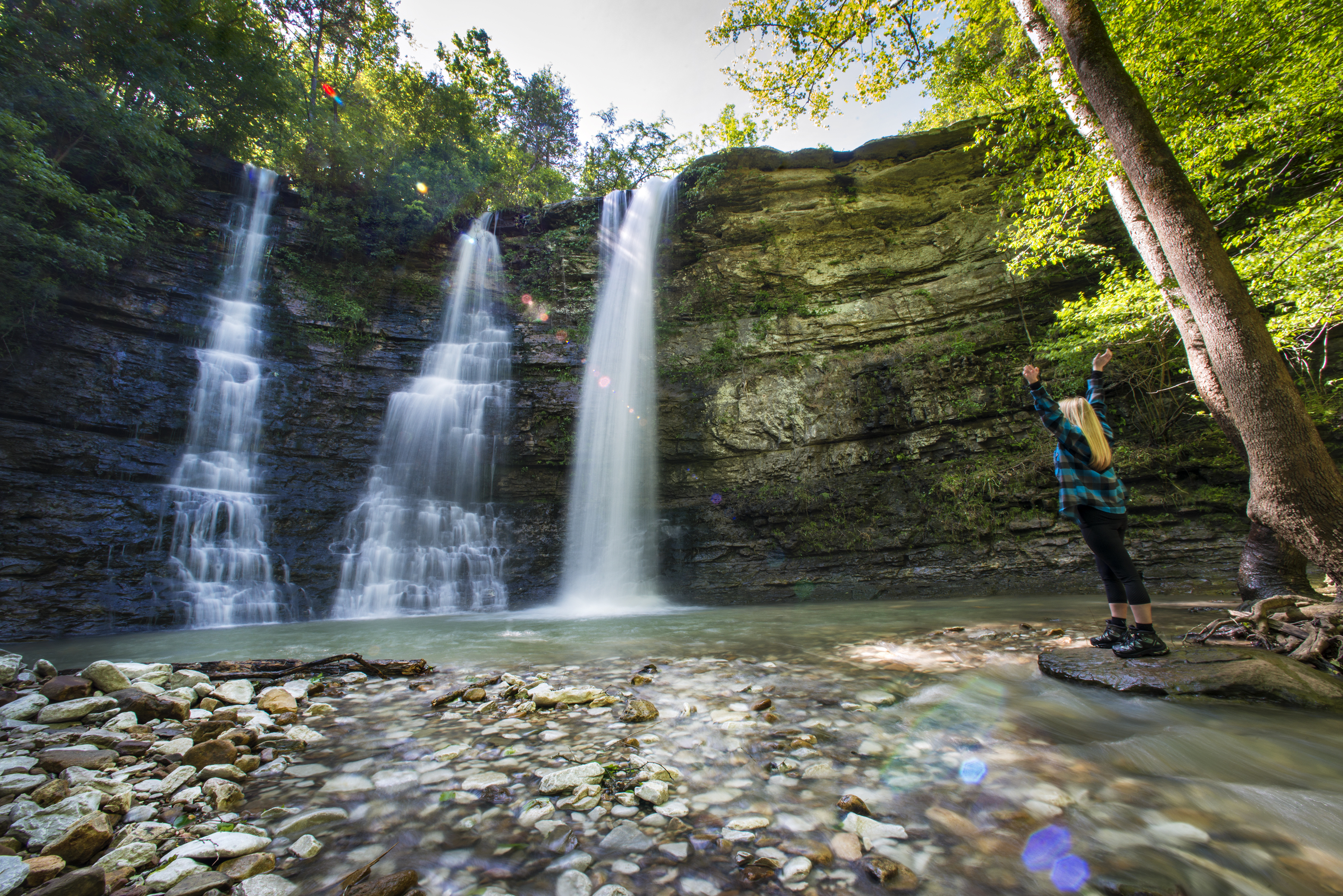 A hiker celebrates as they reach Twin Falls - which has so much water that it has formed three waterfalls as opposed to it's normal two. 